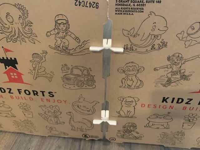 Cardboard play structure with illustrations and 'Kidz Forts' branding.