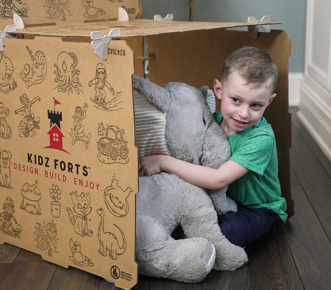 Boy hugging a stuffed elephant while sitting in a kids play fort.