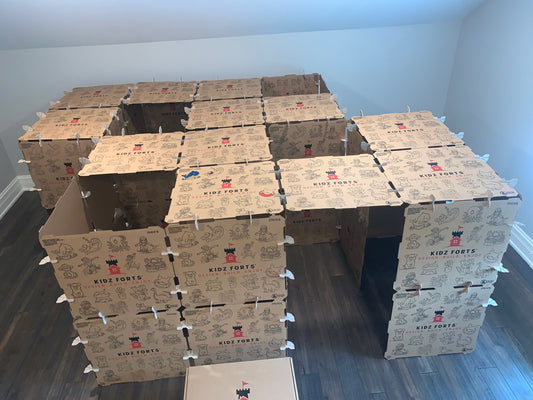 A large cardboard play fort for kits to play inside.
