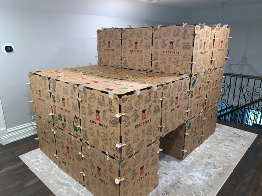 A cardboard play fort with multiple levels, built in a family room.