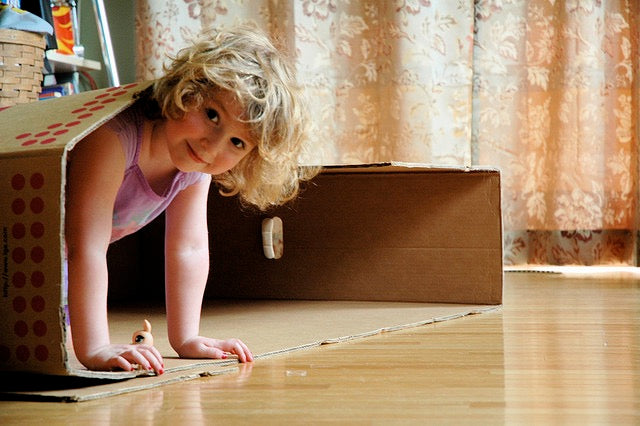 Girl playing in a cardboard box.