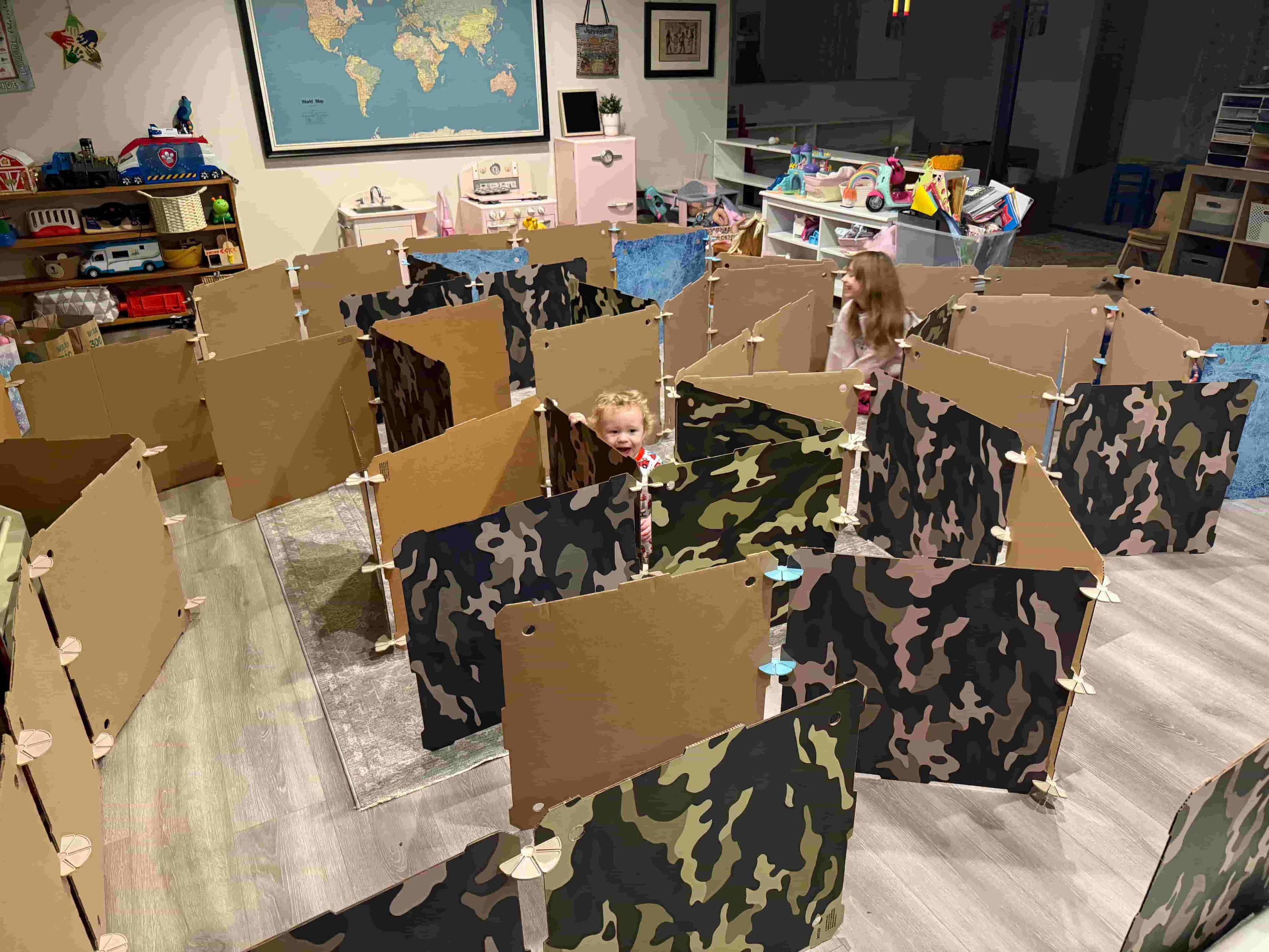 Children building a maze and playing with cardboard play fort building kits.