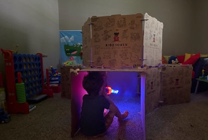 Kidz Forts cardboard play fort kit with a child inside playing with a light-up toy. Durable, eco-friendly, and made in USA.