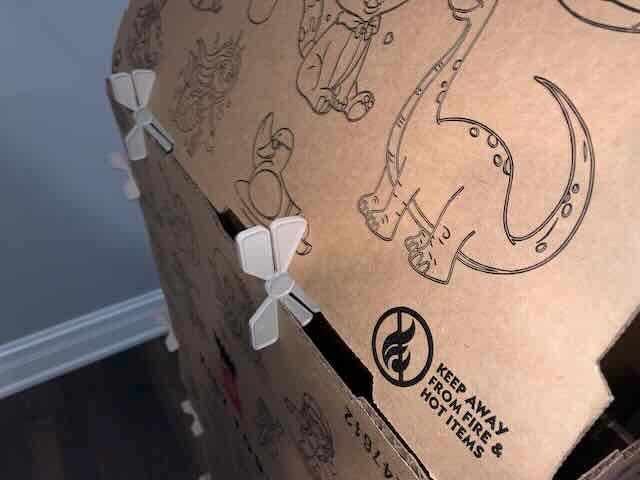 Cardboard box with illustrations and a 'Keep Away from Fire' label on a blue wall background.