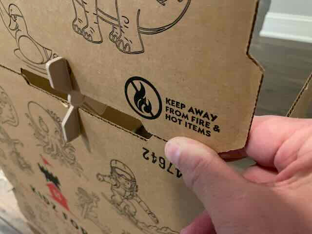 Cardboard box with a flame warning label and a hand pointing to it.