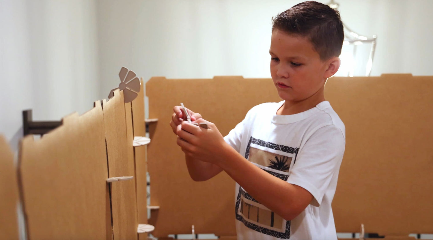 A handsome boy with a white T-shirt, putting a connector on a children's play fort.