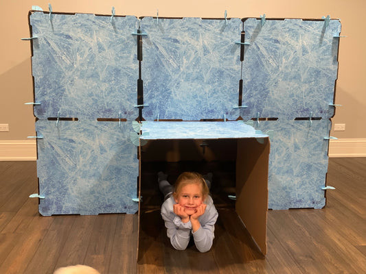 Kidz Forts Frosted Kit play fort with ice pattern panels and cardboard entrance. A young girl lies inside.